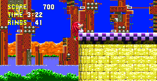 As Knuckles, you'll recall your earlier arson crimes and find a solid stump where that building used to be. Simply climb the wall and run across the top into an opening on the far side..