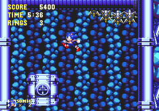 The first of Sonic's rings is on his main route from Point #7. Look for a tall room with a red spring in the corner, and these spikeballs swinging around the ceiling above. Aim to land on this block in the middle and jump into the left hand wall.